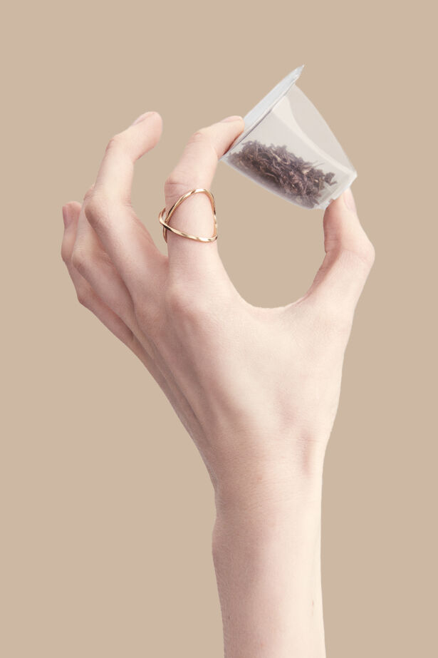 Hand holding up a tea capsule with organic tea