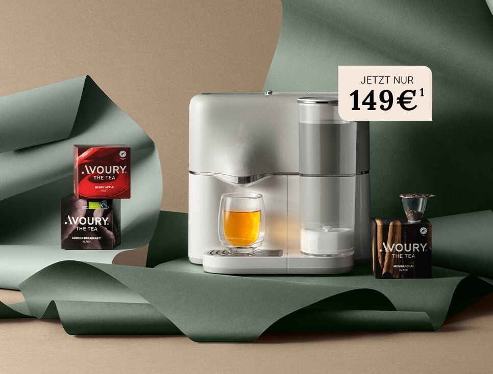 Die Avoury One teemaschine in silver/white mit 3 Texboxen und einem gefülltem Teeglas vor grün farbenem Hintergrund arrangiert.