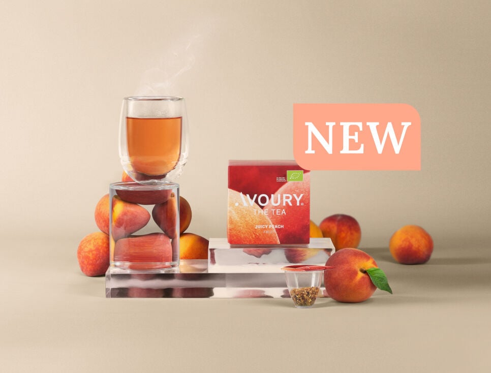 Peaches, a glass of steaming tea, a tea capsule, and a peach tea box labeled “Avoury The Tea Juicy Peach