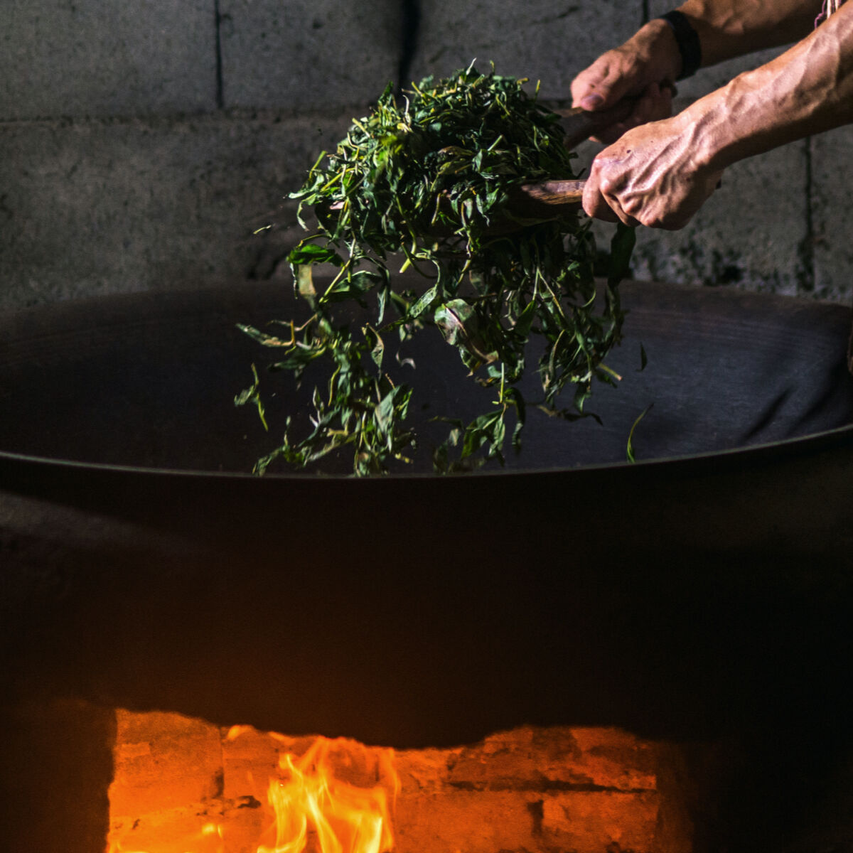 tea leaves in a pot over fire to be dried