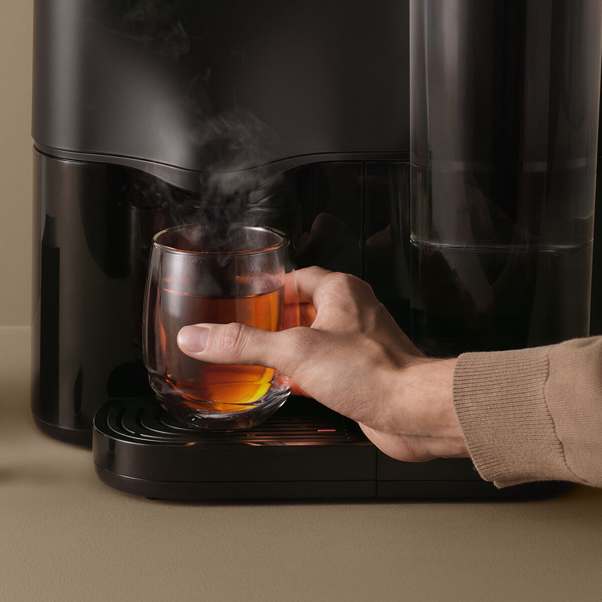 Avoury One tea machine in black with a glass of tea